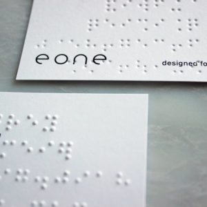 Showing front and backside of the eone business card, showing the braille embossing